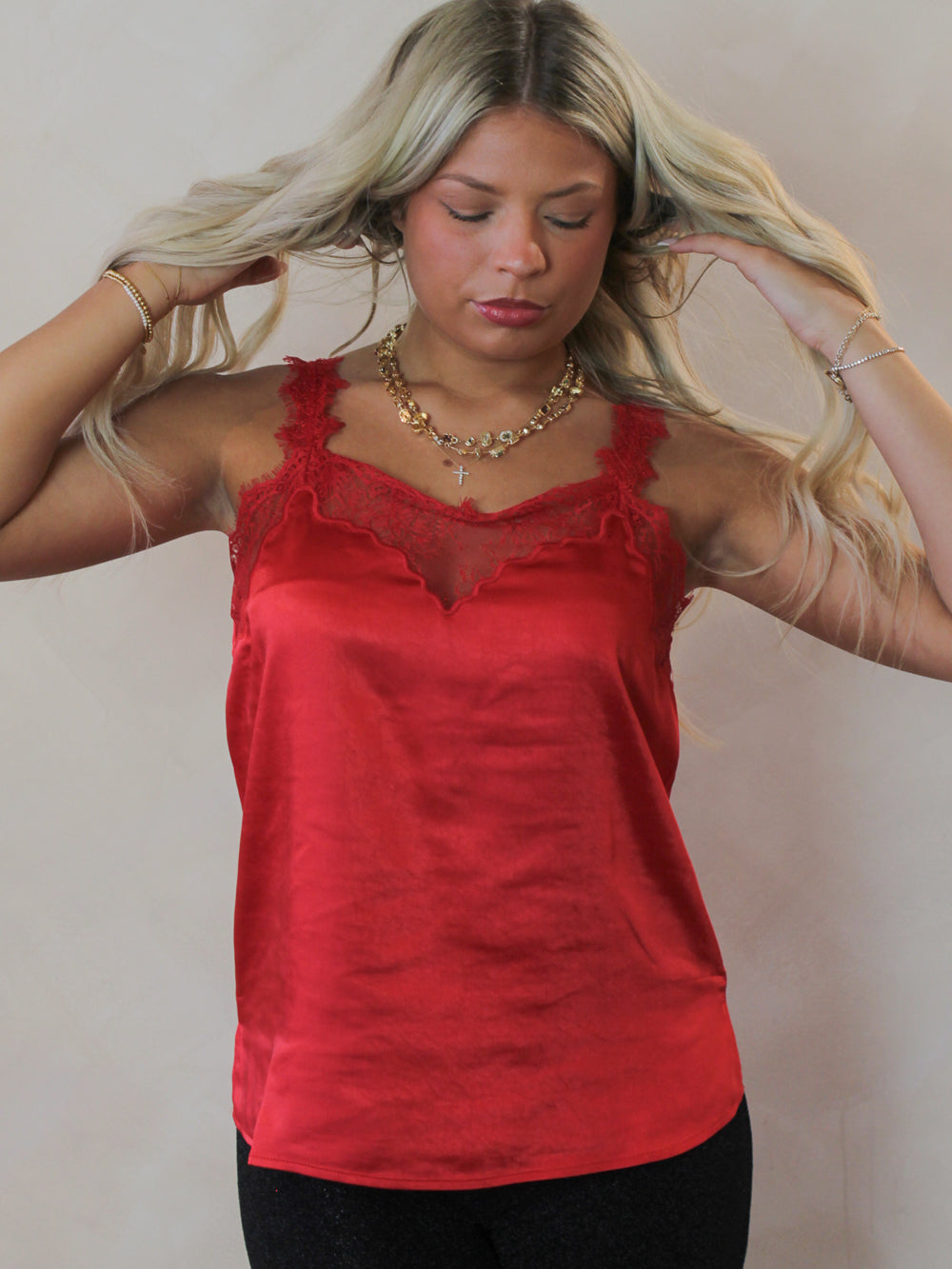 Model wearing a red, satin tank top with lace trim 