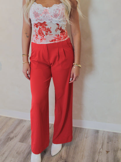 Model wearing a floral mesh tank top and red trouser pants 