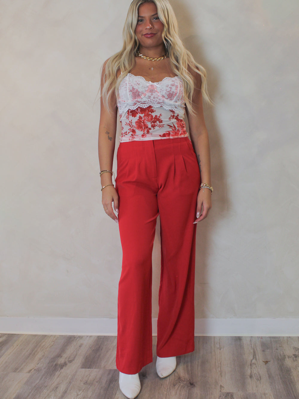Woman wearing a pair of red trousers with a floral mesh tank 