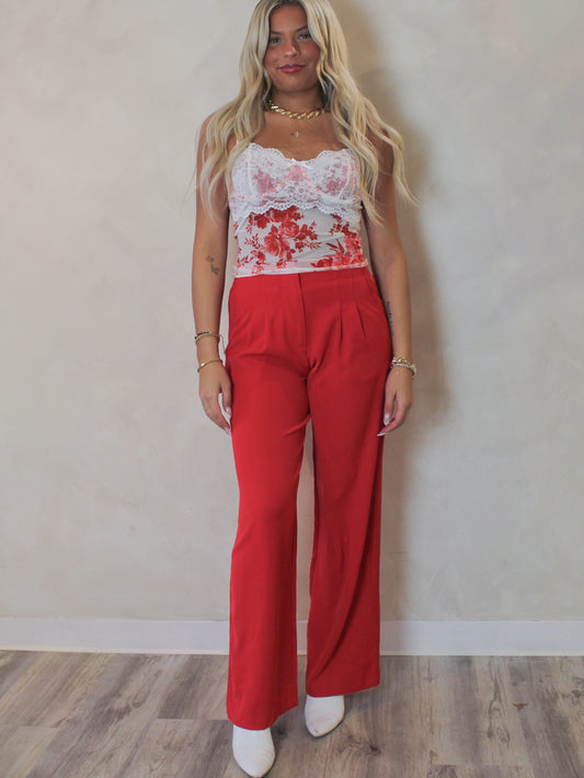Woman wearing a pair of red trousers with a floral mesh tank 