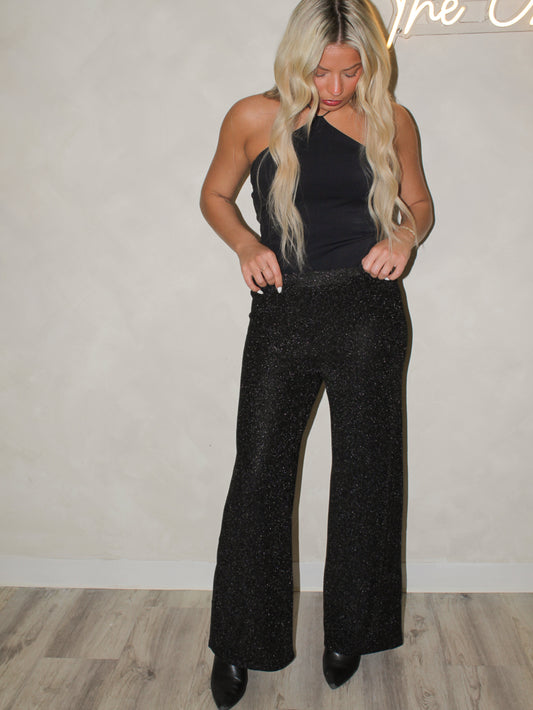 Model wearing a pair of black shimmer pants with silver shimmer