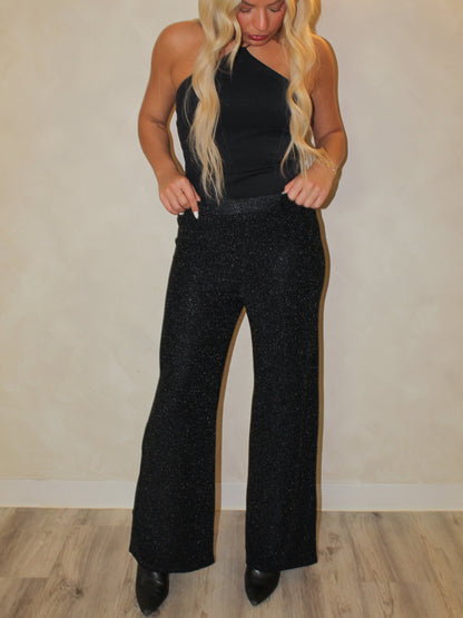 Model wearing black shimmer pants and black top for the holiday