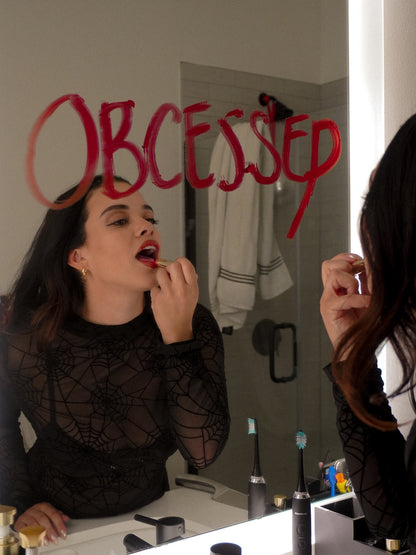 Woman wearing a black mesh top featuring an all over spiderweb print 