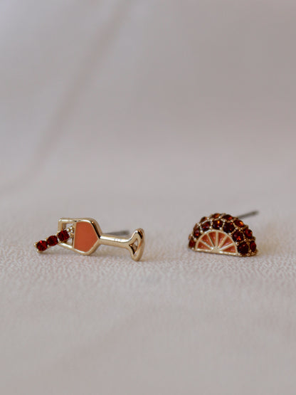 A pair of stud earrings one is a spritz drink and the other an orange slice