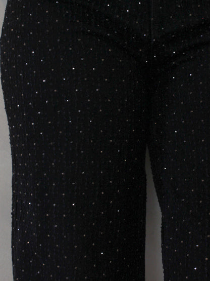 Close-up of black pants with gold sparkly rhinestone details 