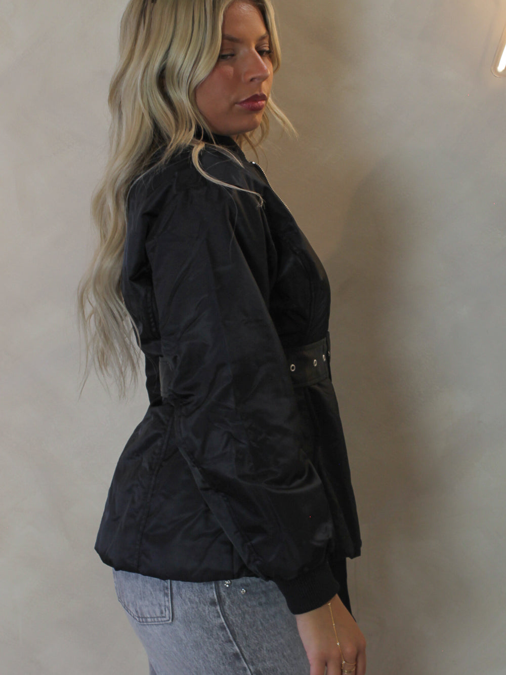 Model wearing a black belted nylon jacket 