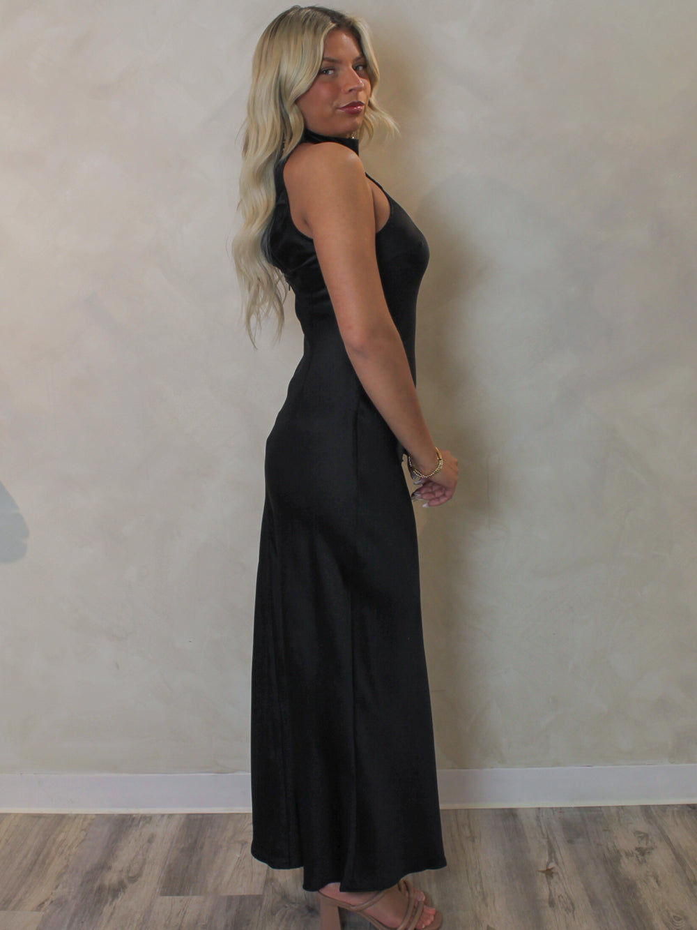 Model wearing a sleeveless, black satin slip dress