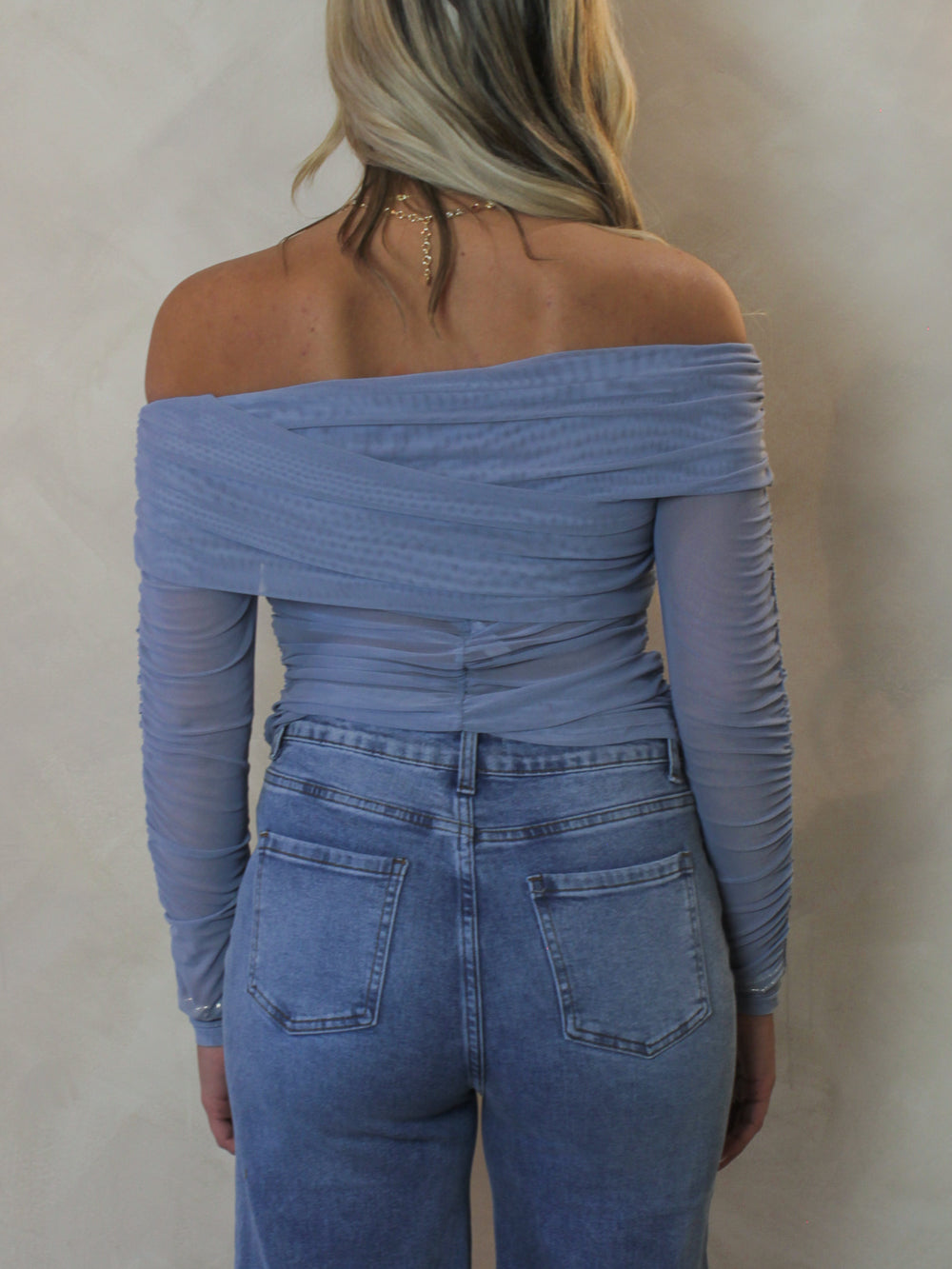 Model wearing a light blue off the shoulder mesh top for spring 