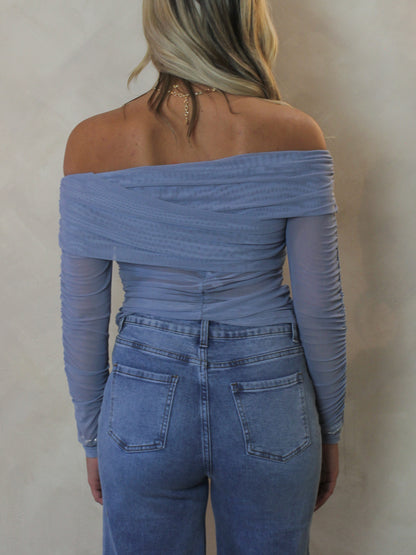 Model wearing a light blue off the shoulder mesh top for spring 