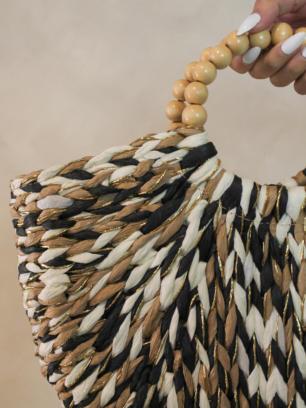 Detail view of woven handbag with a beaded handle for summer