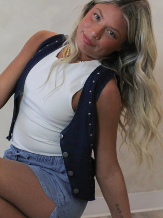 Woman wearing a white top and blue denim vest