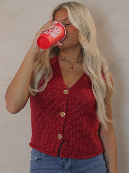 Woman wearing a red sweater vest with gold buttons 