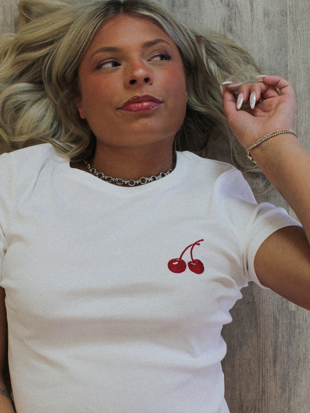 Girl wearing a white tee with embroidered cherry detail 