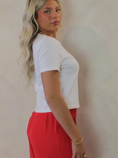 Model wearing a white, short sleeve top with a shorter hem 