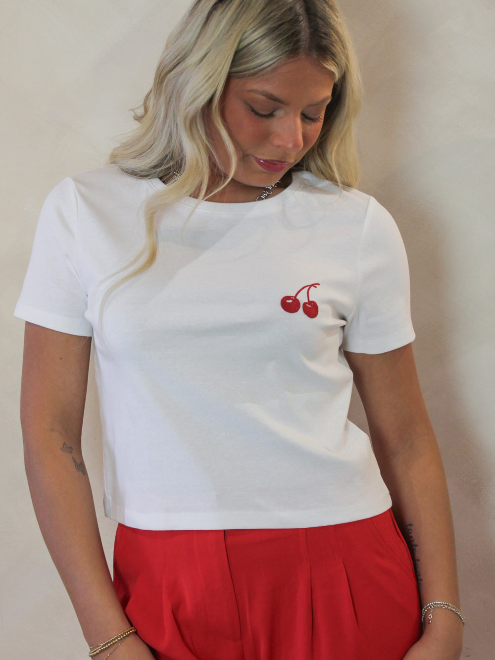 Model wearing a white short sleeve tee with embroidered cherry detail 