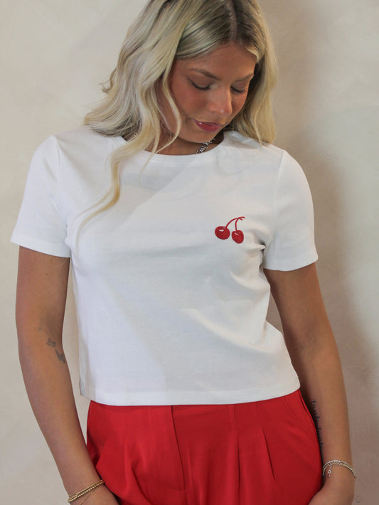 Model wearing a white short sleeve tee with embroidered cherry detail 