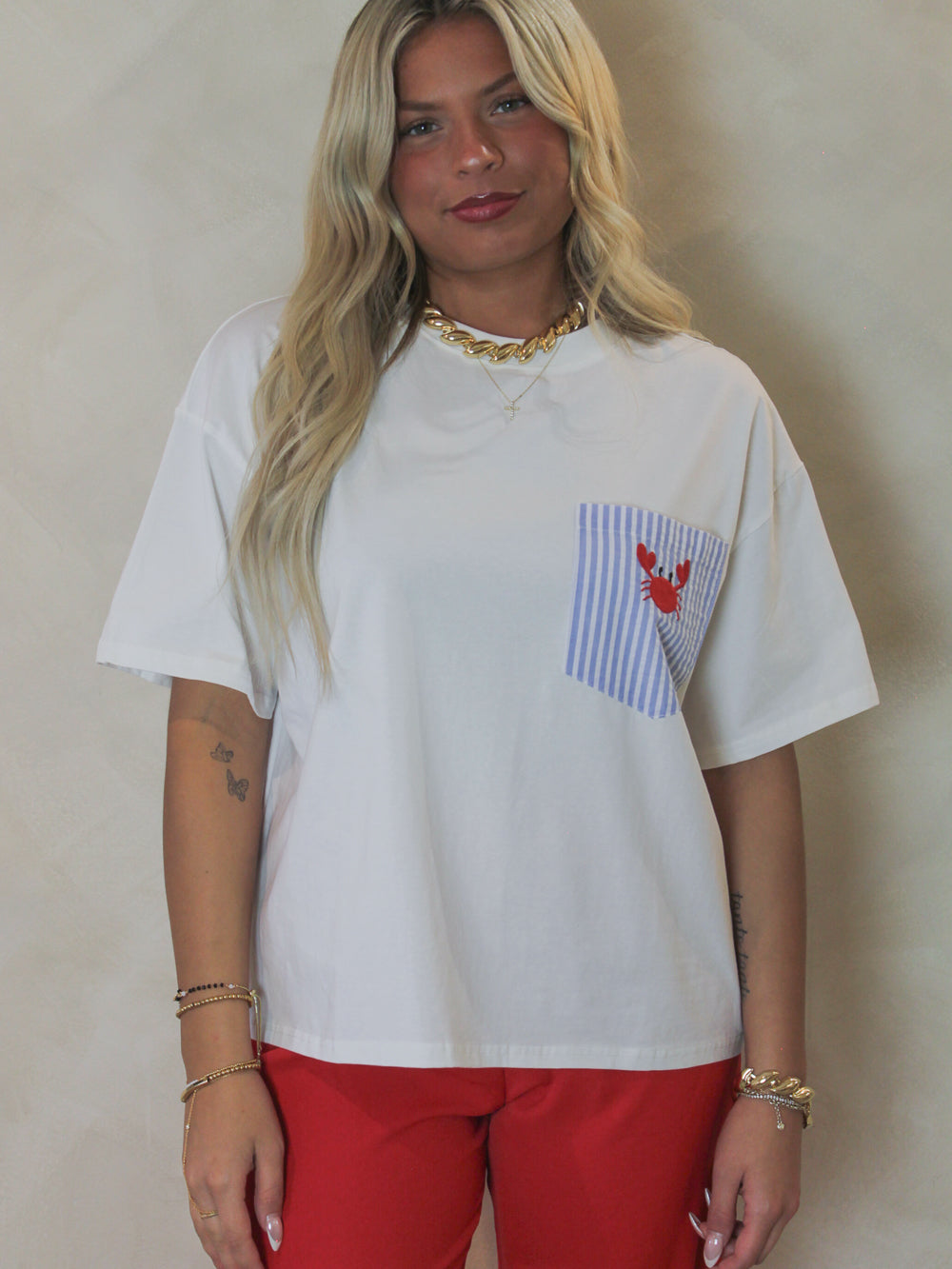 Model wearing a white boxy tee with an embroidered crab graphic 