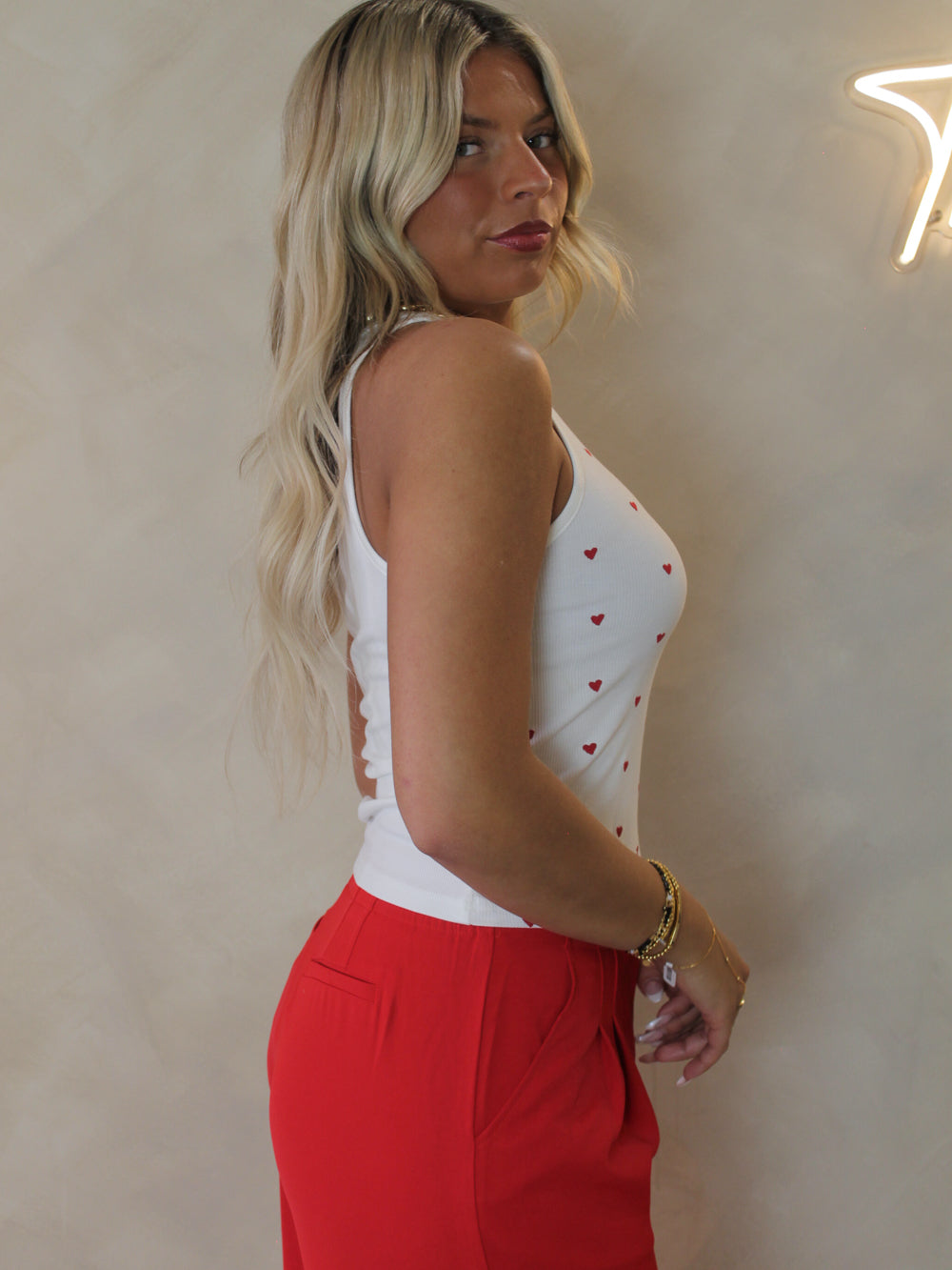 Model wearing a ribbed tank with little red hearts all over the front 