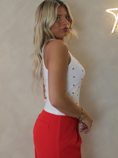 Model wearing a ribbed tank with little red hearts all over the front 