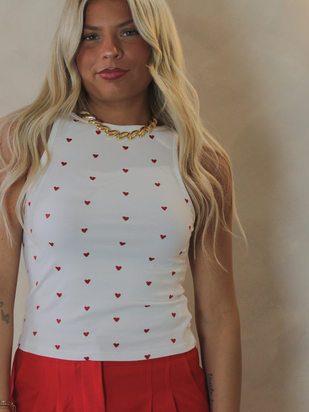 Girl wearing a white ribbed tank with embroidered hearts all over 