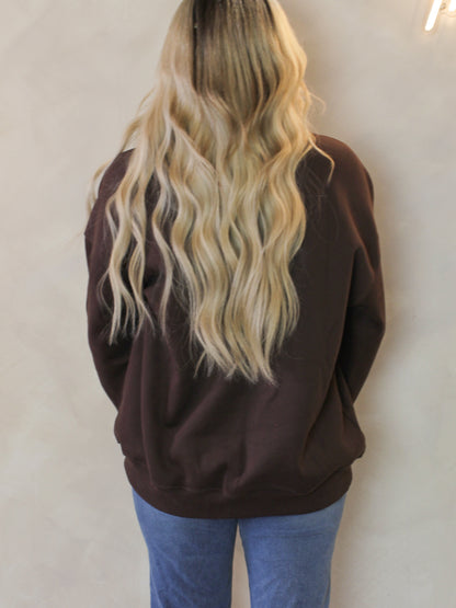 Woman wearing a brown crewneck sweatshirt 