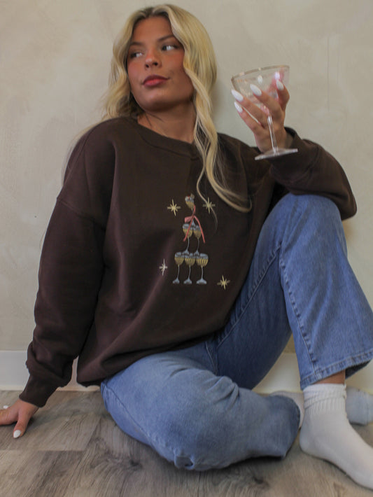 Girl wearing a brown sweatshirt with an espresso martini tower graphic 
