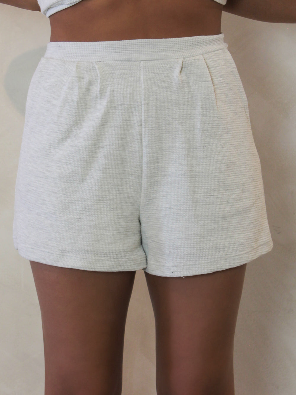 Front view of a pair of white ribbed shorts 