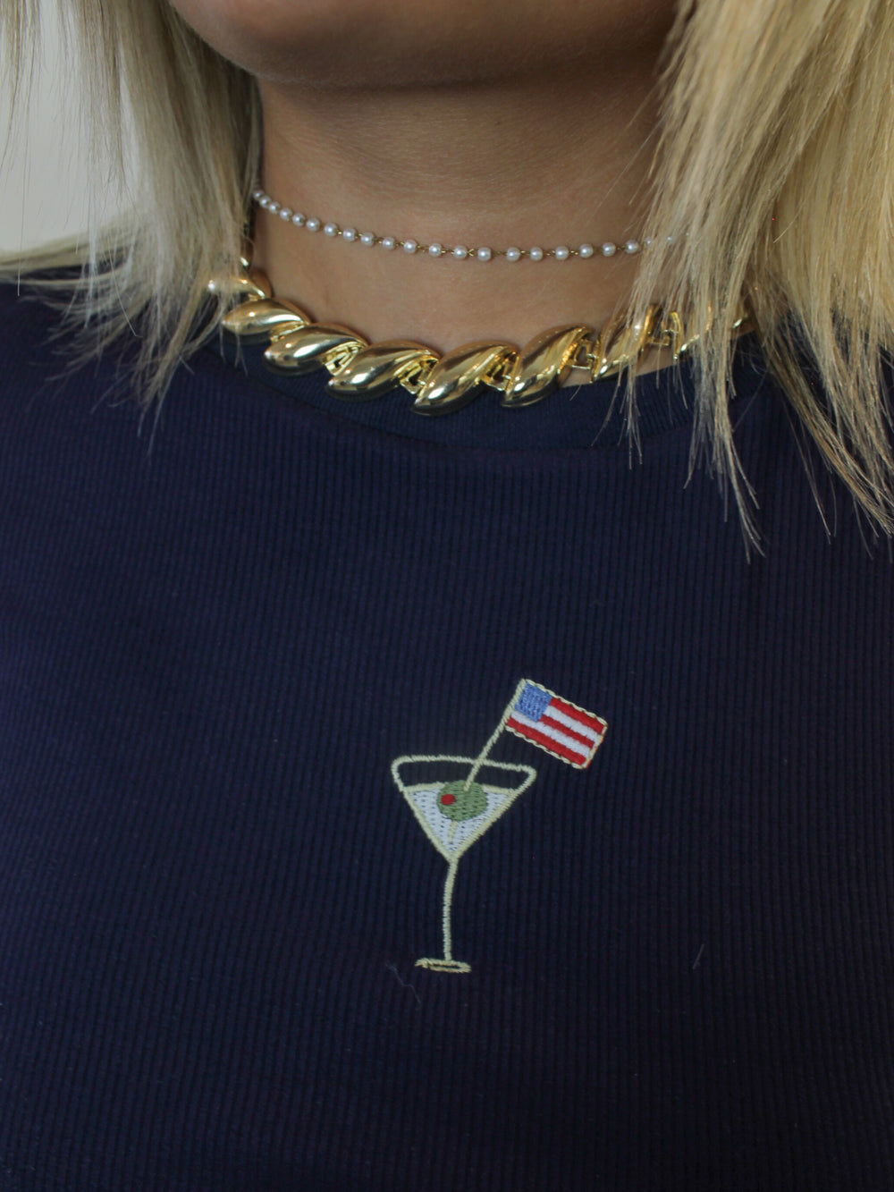 A navy blue ribbed tee shirt with an embroidered martini and American flag graphic
