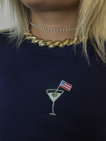 A navy blue ribbed tee shirt with an embroidered martini and American flag graphic