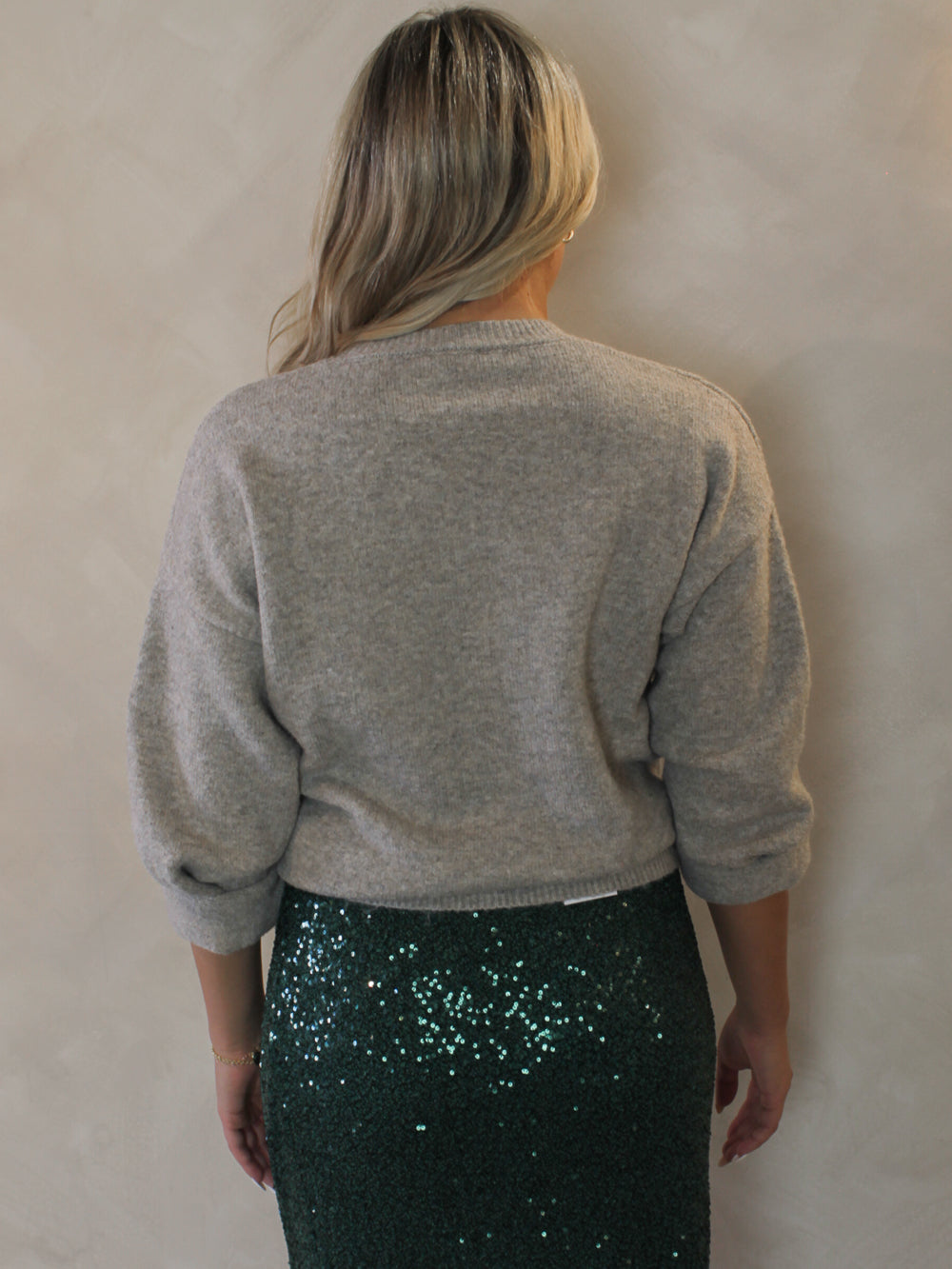 Model  wearing a gray sweater and green sequin skirt