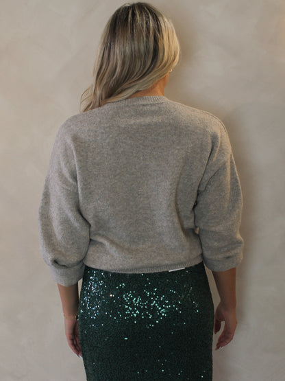 Model  wearing a gray sweater and green sequin skirt