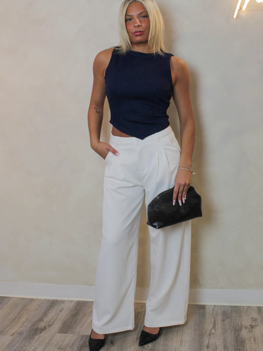 woman wearing a white trouser outfit with a denim top and heels.