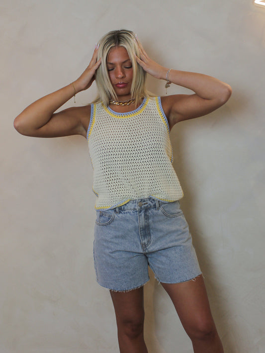 woman wearing butter yellow, knit tank with contrast blue and yellow trim.
