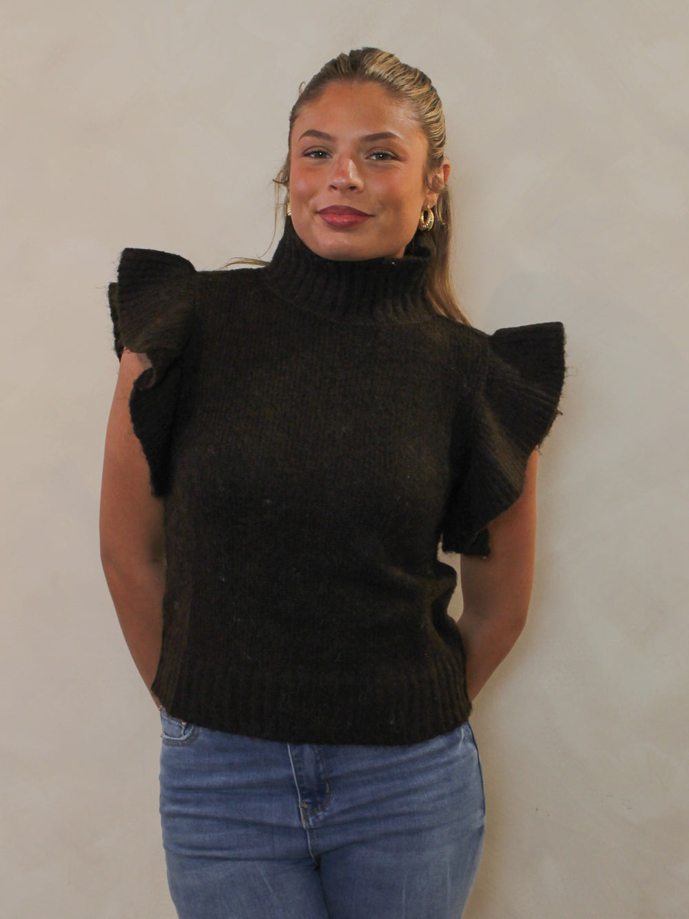 Dark brown ribbed sweater with a mock neck and dramatic ruffle cap sleeves.