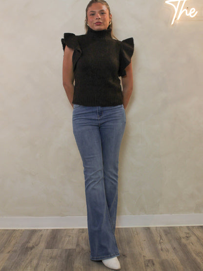 Dark brown ribbed sweater with a mock neck and dramatic ruffle cap sleeves styled with light blue flare jeans.