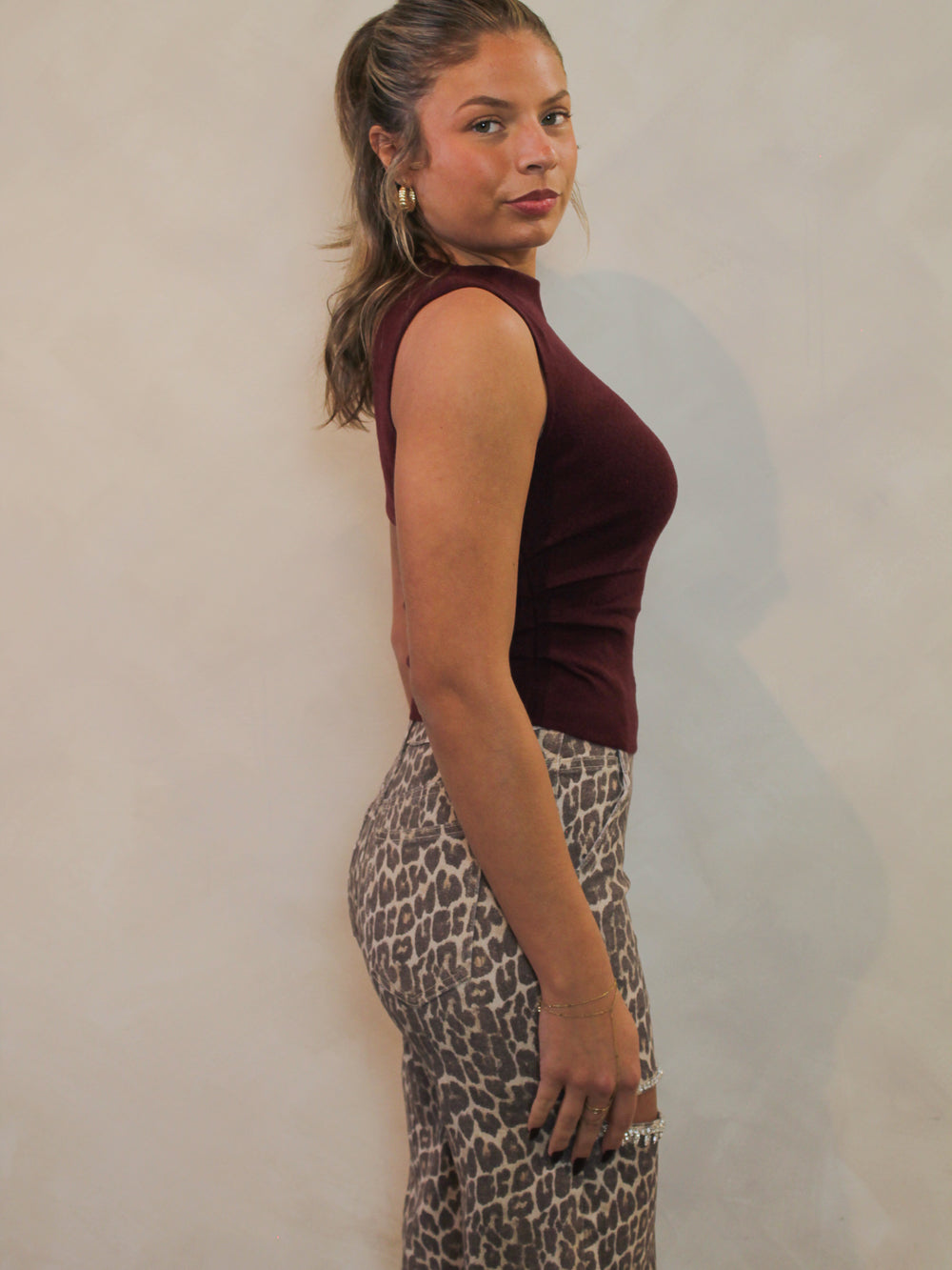 Side view of a wine colored knit top with an off-the-shoulder silhouette.