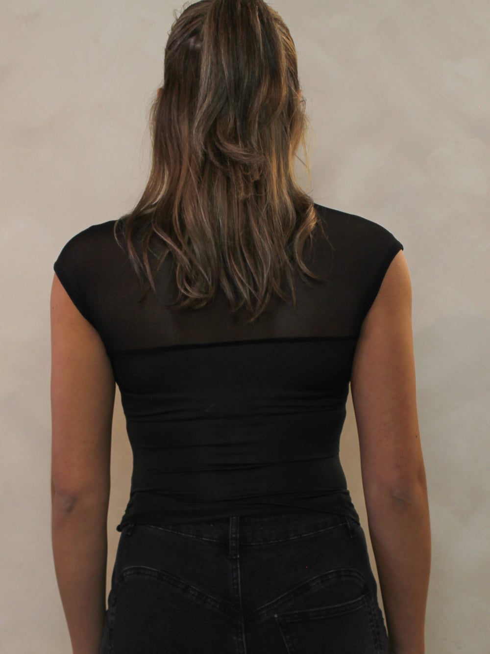 Back view of a black top with a mesh neckline