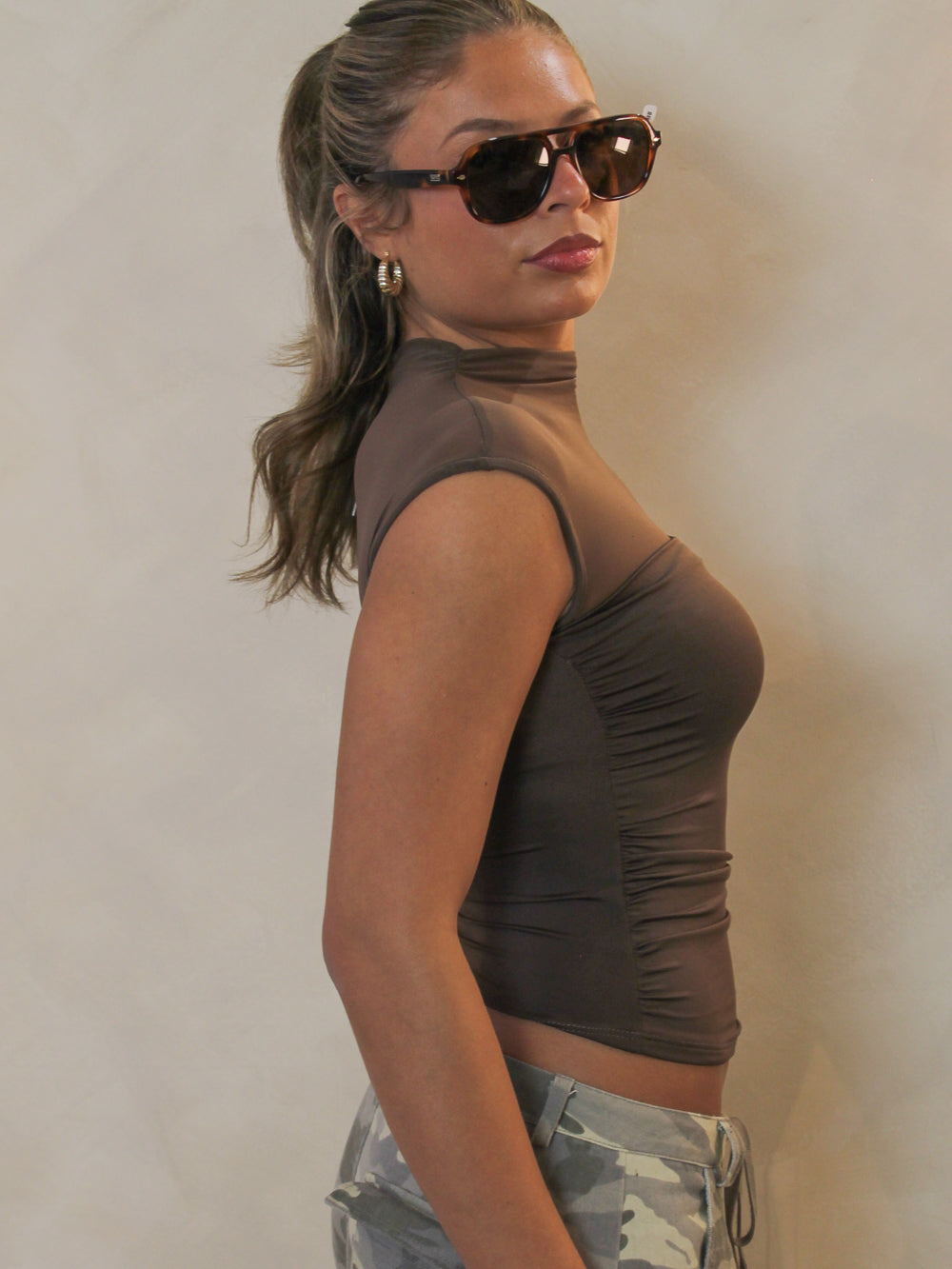 Side view of a brown short sleeve dressy top with a sheer mesh neckline.