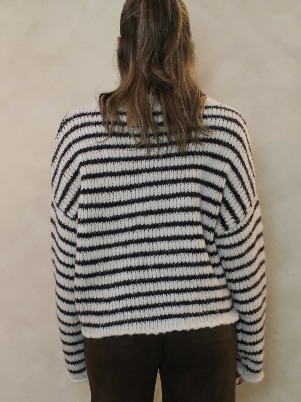 Back view of a white and chocolate brown striped sweater.