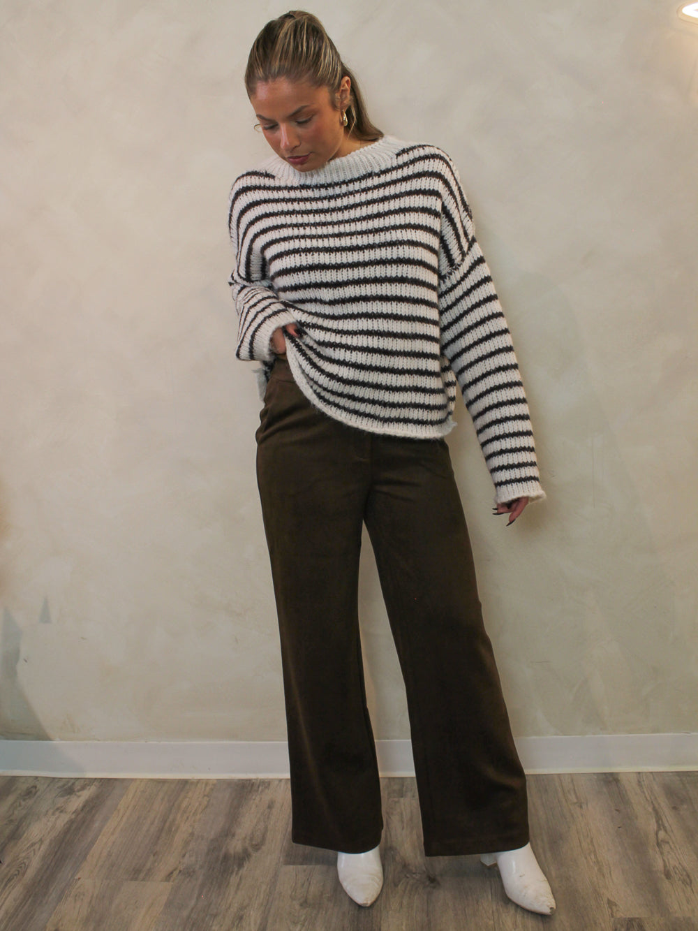 White and chocolate brown striped sweater paired with brown pants and white boots.