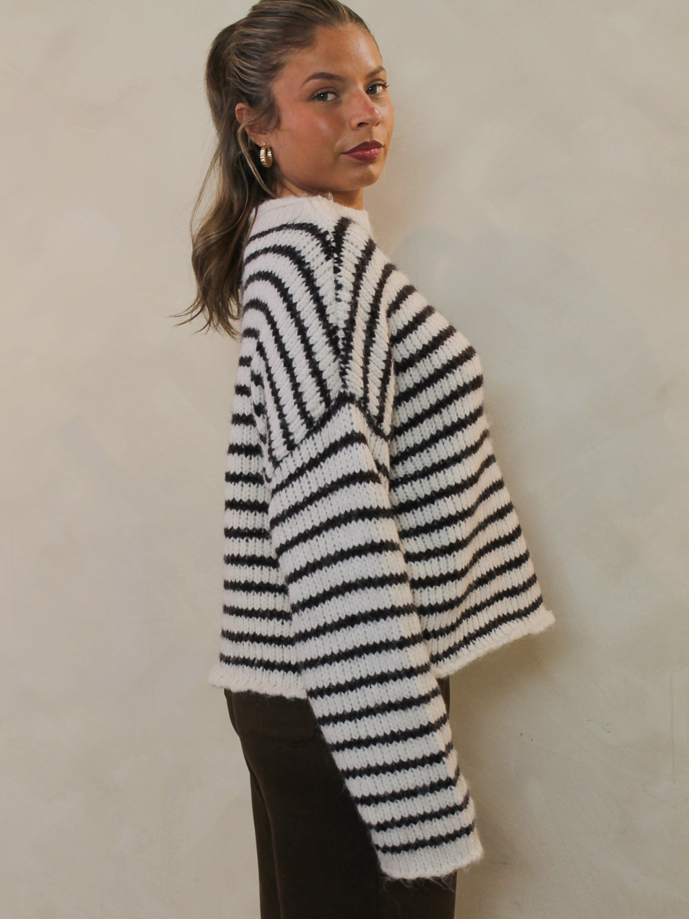Side view of a white and chocolate brown striped sweater.