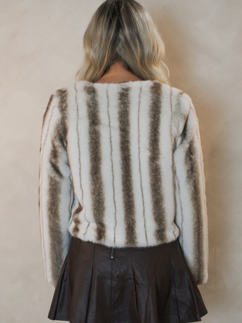 Back view of a cream faux fur jacket with brown striped detail