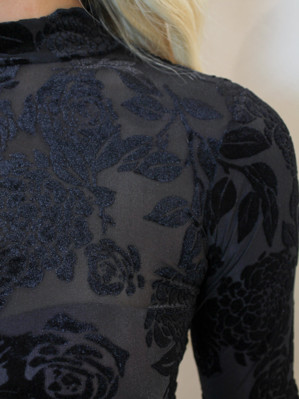 Detail view of a floral velvet, mesh, long sleeve top