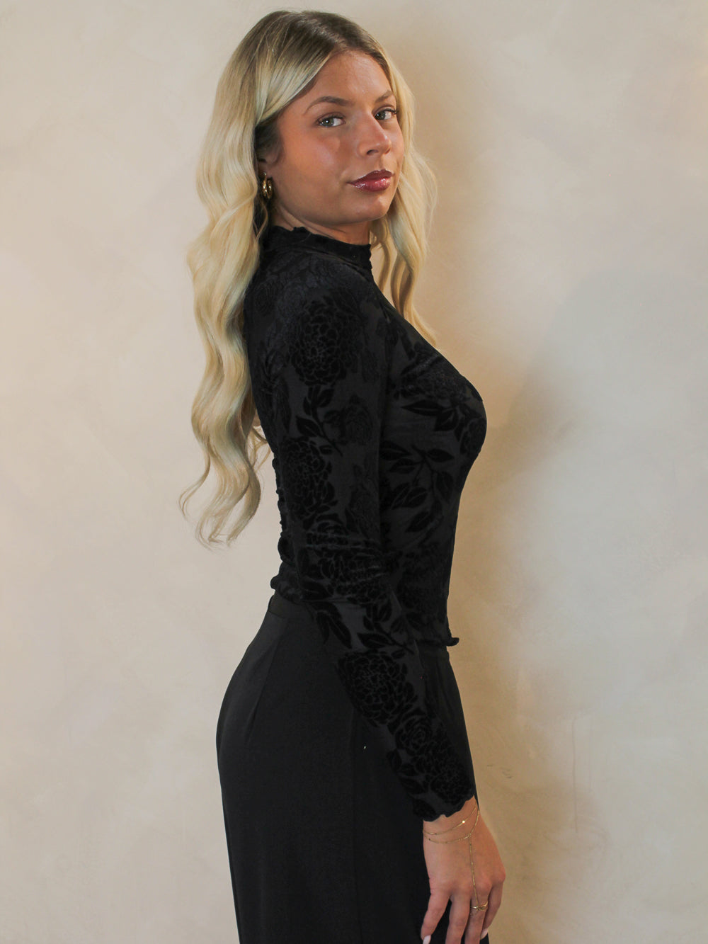 Side view of a woman wearing a long sleeve, black floral top