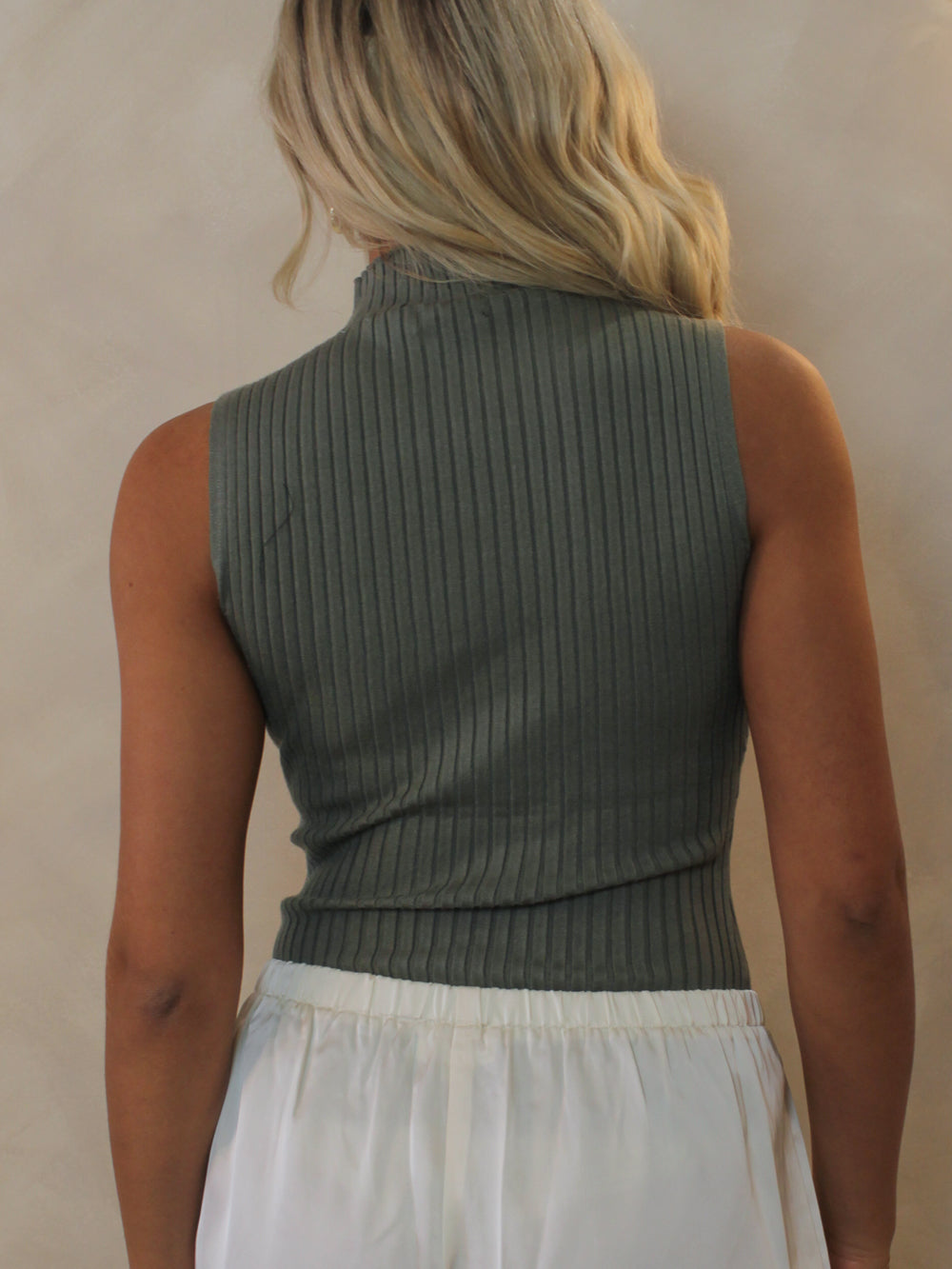 A woman shown from the back wearing a sleeveless ribbed knit mock neck top in an olive green color