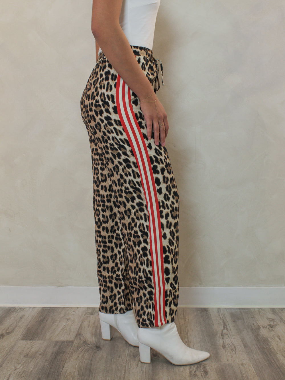Leopard pants with red and white stripe paired with a white tank and white booties outfit 