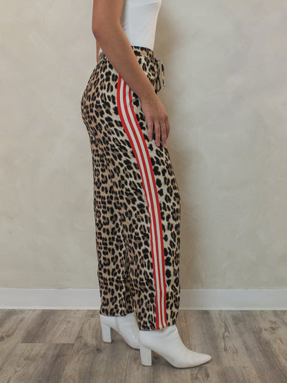 Leopard pants with red and white stripe paired with a white tank and white booties outfit 