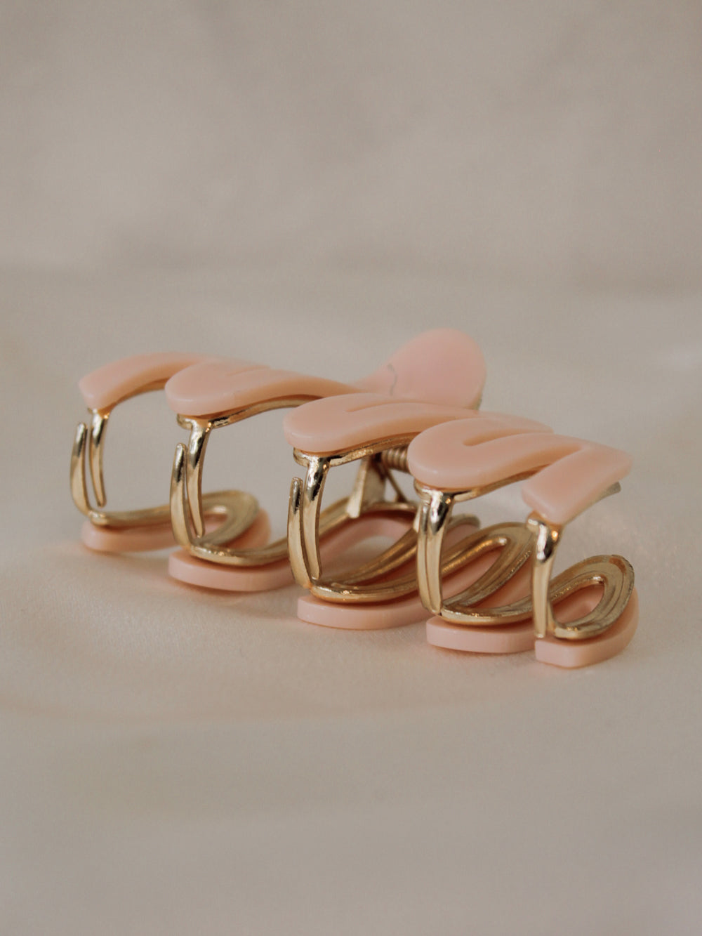 the side view of a gold and pink claw clip with a wavy design  for women
