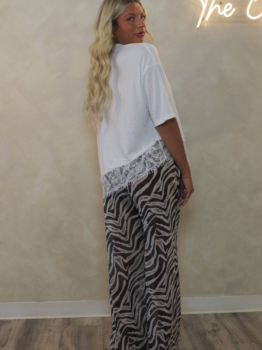 Model wearing an oversized white tee with lace trim and zebra pattern pants