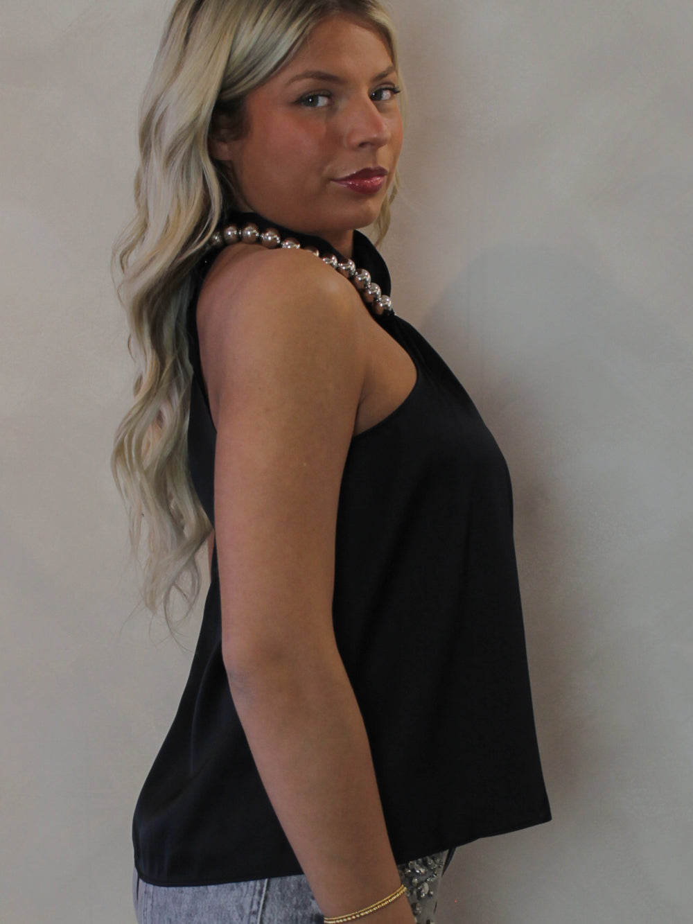 Model wearing a black halter top with a silver necklace detail 